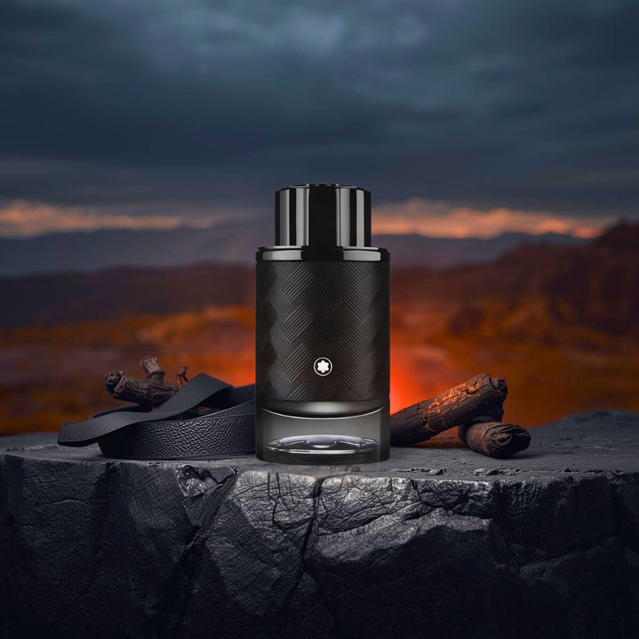 Flakon perfum Montblanc Explorer Extreme stoi na ciemnym kamieniu w świetle zachodzącego słońca. W tle widać góry i bursztynowe refleksy symbolizujące ciepło zapachu.